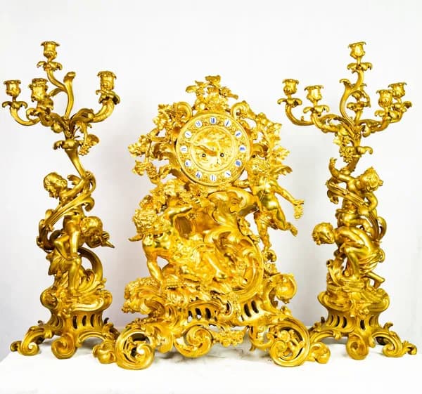 Fire-gilded three-piece clock set with rococo-style cherub and satyr depictions