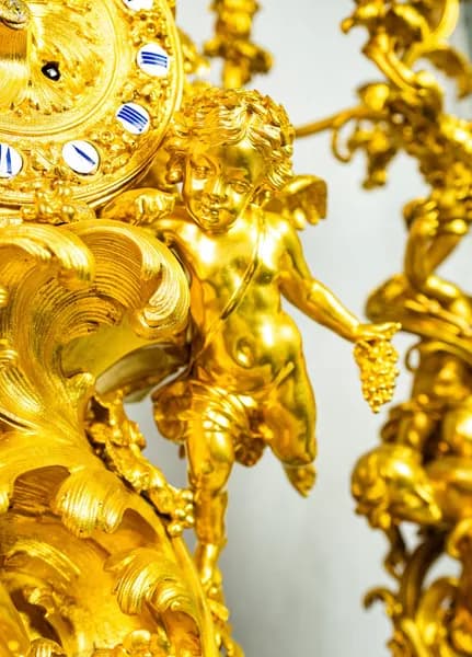 Fire-gilded three-piece clock set with rococo-style cherub and satyr depictions
